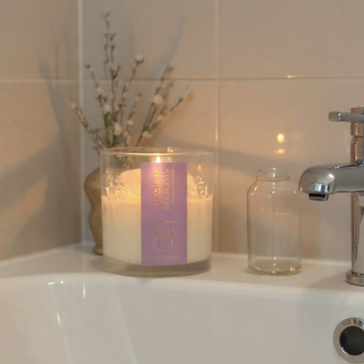 Juniper Blooms coconut wax candle, purple label, glass jar in a bathroom