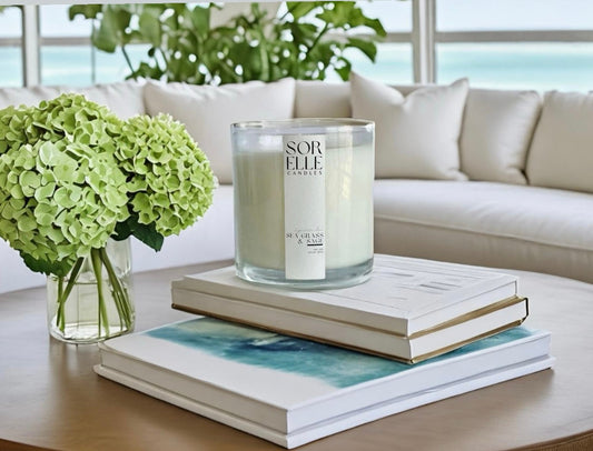 Neutral-toned luxury candles styled in a warm, cozy living room with a soft throw, natural light, and a minimalist ceramic holder — perfect housewarming vibes.