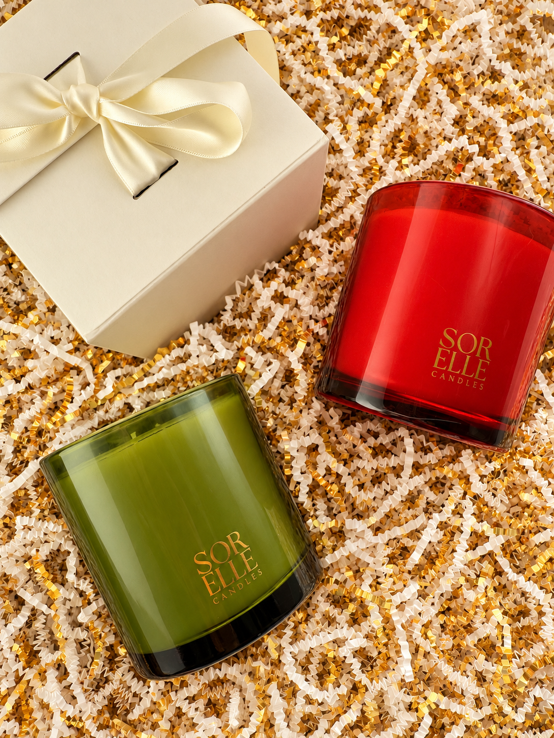 Balsam Forest and Merry & Bright candles beside a ribbon-tied ivory gift box on gold crinkle paper