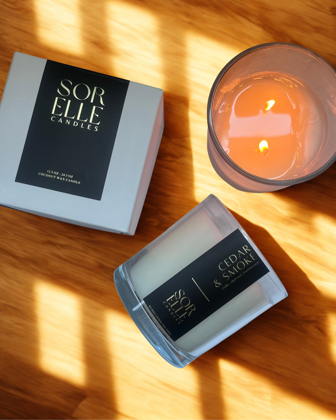 Flat lay of Cedar & Smoke candle with dried wood, charcoal pieces, and vintage leather accents on cedarwood